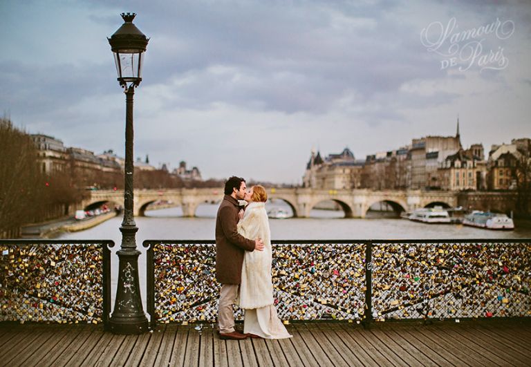 A couple locking their padlocks onto the Pont Des Arts bridge in Paris in a romantic tradition to celebrate their love.