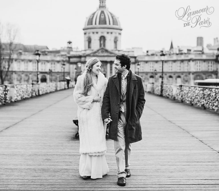 A couple locking their padlocks onto the Pont Des Arts bridge in Paris in a romantic tradition to celebrate their love.