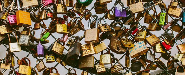 A couple locking their padlocks onto the Pont Des Arts bridge in Paris in a romantic tradition to celebrate their love.