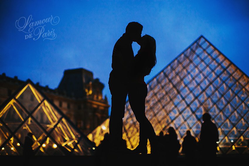 Romantic couples portrait session of Allison Morton and Ahmed Soualhi in Paris France in the courtyard of the Louvre pyramid at night by Paris portrait photographer Stacy Reeves for L'Amour de Paris photography studio.