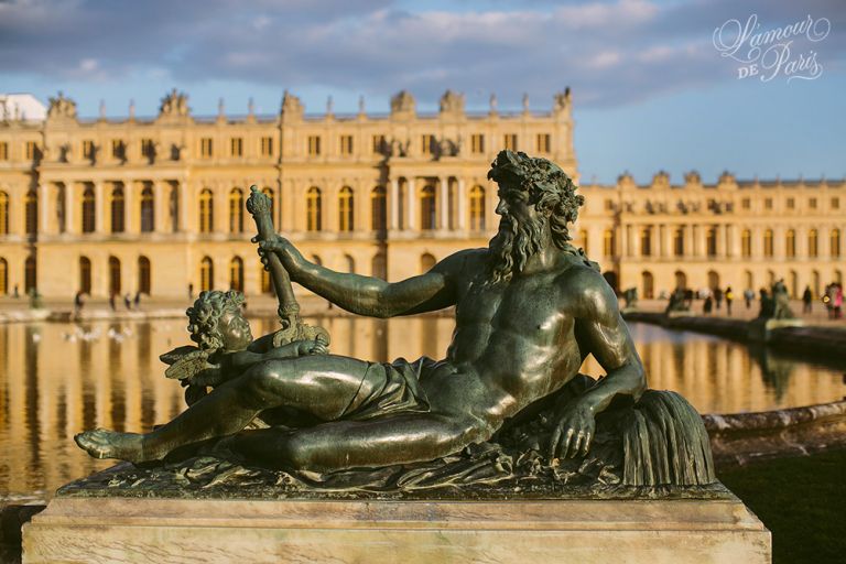 The art sculptures and the grand chateau of Versailles outside of Paris France