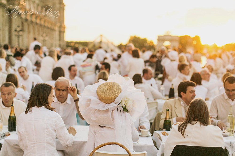 Diner en Blanc, also known as Diner in White, a top secret invitiation-only flash mob in Paris, France where 11,000 people dressed entirely in white clothes spontaneously set up tables and chairs in front of historic landmarks one night a year. The 2013 Diner en blanc, held on July 13, took place in the Louvre courtyard and by the Trocadero fountains in front of the Eiffel Tower. Photographed by Paris wedding and portrait photographer Stacy Reeves for vacation planning blog L'Amour de Paris.