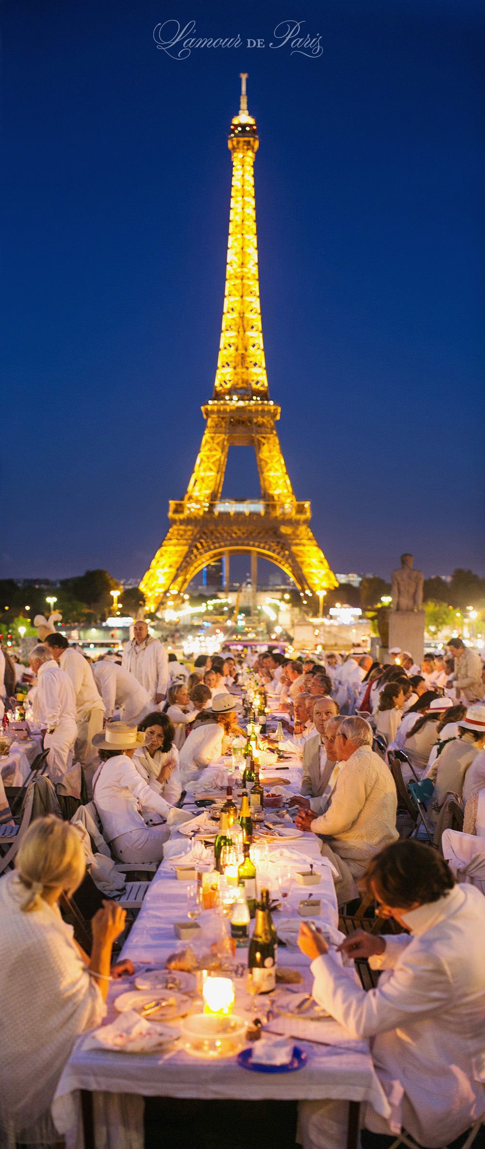 Diner en Blanc, also known as Diner in White, a top secret invitiation-only flash mob in Paris, France where 11,000 people dressed entirely in white clothes spontaneously set up tables and chairs in front of historic landmarks one night a year. The 2013 Diner en blanc, held on July 13, took place in the Louvre courtyard and by the Trocadero fountains in front of the Eiffel Tower. Photographed by Paris wedding and portrait photographer Stacy Reeves for vacation planning blog L'Amour de Paris.