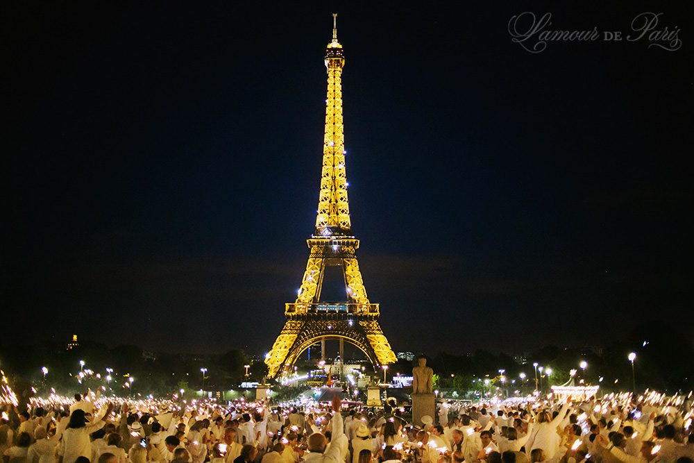Diner en Blanc, also known as Diner in White, a top secret invitiation-only flash mob in Paris, France where 11,000 people dressed entirely in white clothes spontaneously set up tables and chairs in front of historic landmarks one night a year. The 2013 Diner en blanc, held on July 13, took place in the Louvre courtyard and by the Trocadero fountains in front of the Eiffel Tower. Photographed by Paris wedding and portrait photographer Stacy Reeves for vacation planning blog L'Amour de Paris.