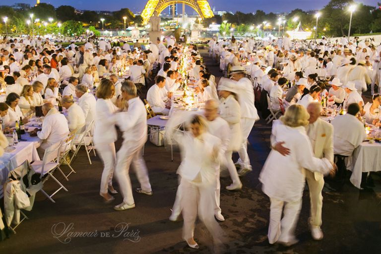 Diner en Blanc, also known as Diner in White, a top secret invitiation-only flash mob in Paris, France where 11,000 people dressed entirely in white clothes spontaneously set up tables and chairs in front of historic landmarks one night a year. The 2013 Diner en blanc, held on July 13, took place in the Louvre courtyard and by the Trocadero fountains in front of the Eiffel Tower. Photographed by Paris wedding and portrait photographer Stacy Reeves for vacation planning blog L'Amour de Paris.