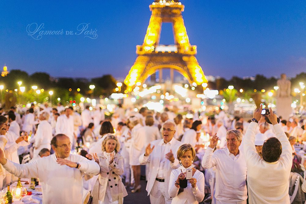 Diner en Blanc, also known as Diner in White, a top secret invitiation-only flash mob in Paris, France where 11,000 people dressed entirely in white clothes spontaneously set up tables and chairs in front of historic landmarks one night a year. The 2013 Diner en blanc, held on July 13, took place in the Louvre courtyard and by the Trocadero fountains in front of the Eiffel Tower. Photographed by Paris wedding and portrait photographer Stacy Reeves for vacation planning blog L'Amour de Paris.