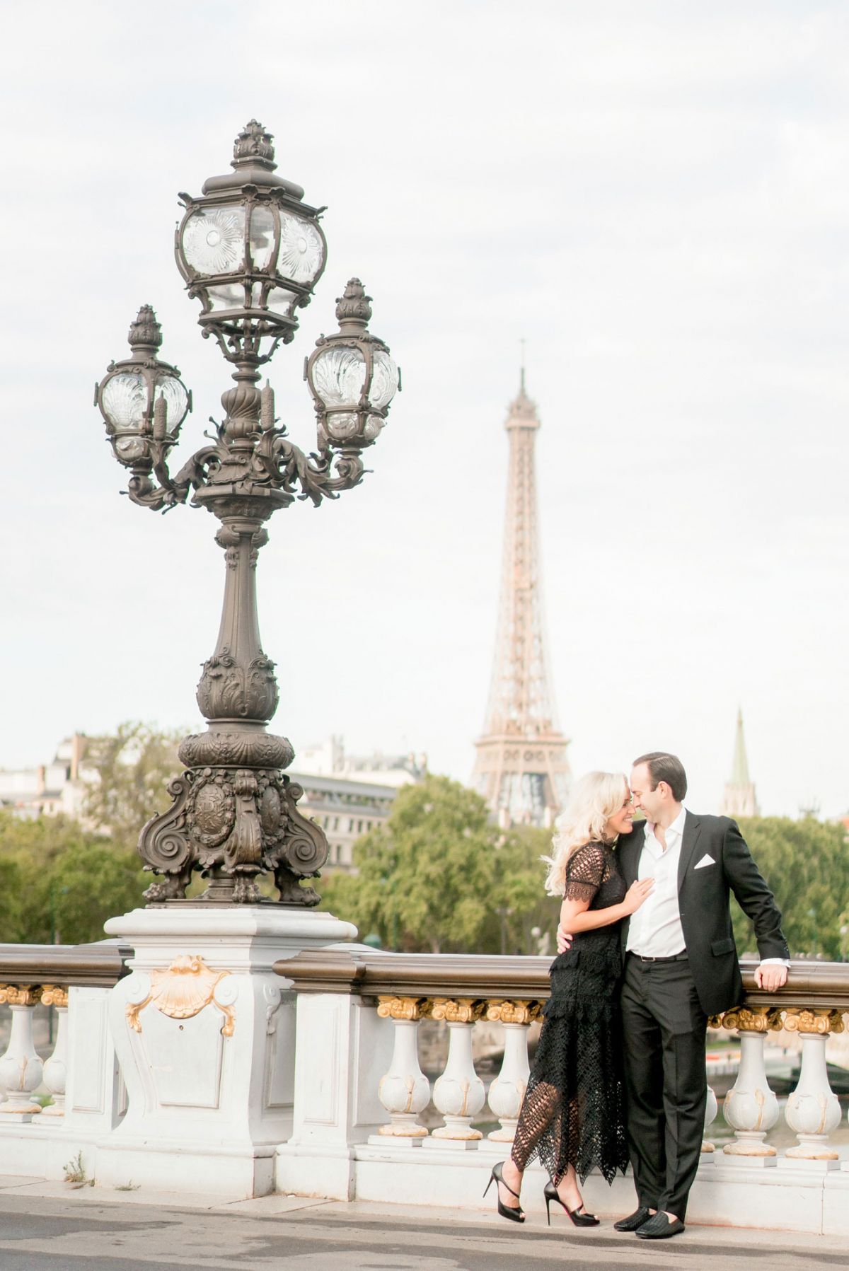 couple snuggles on pont alexandre bridge in paris