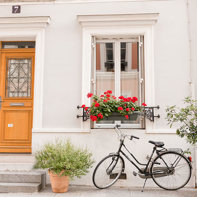 paris bike outside window with red flower box and pretty wood door