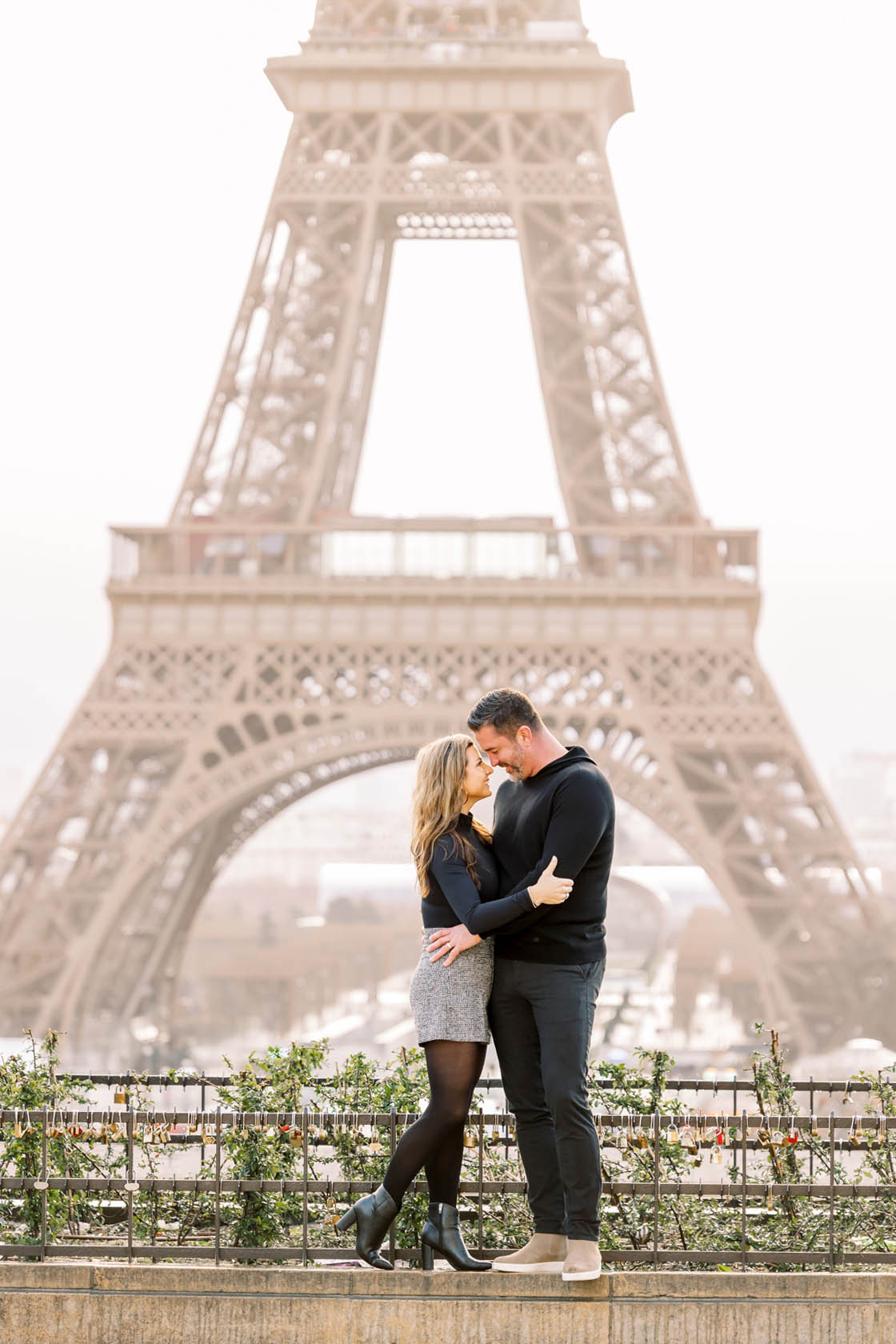 romantic portrait of a couple embracing in front of the eiffel tower early in the morning