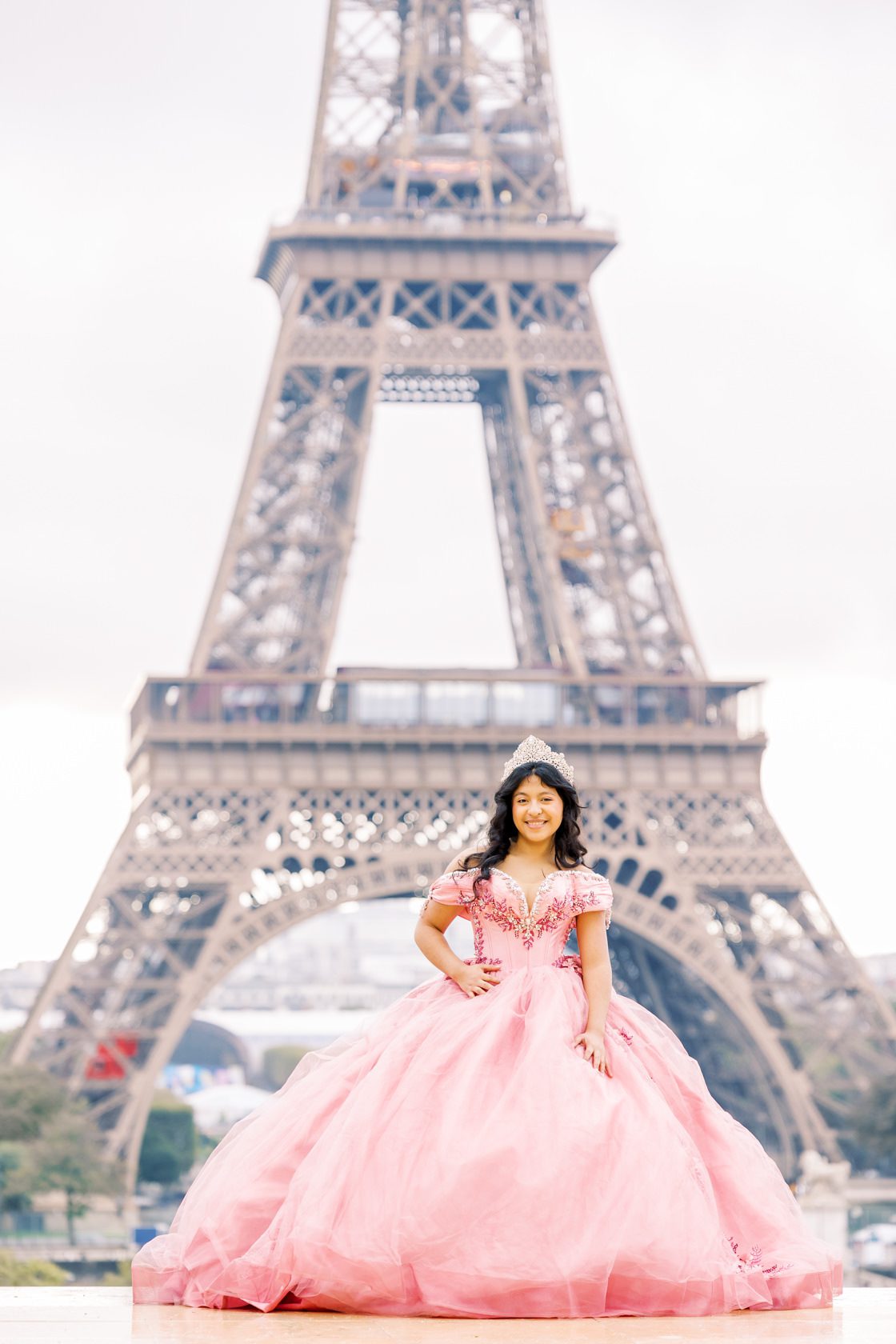 stylish portrait from a quinceanera photoshoot in paris in front of the eiffel paris in a pink dress