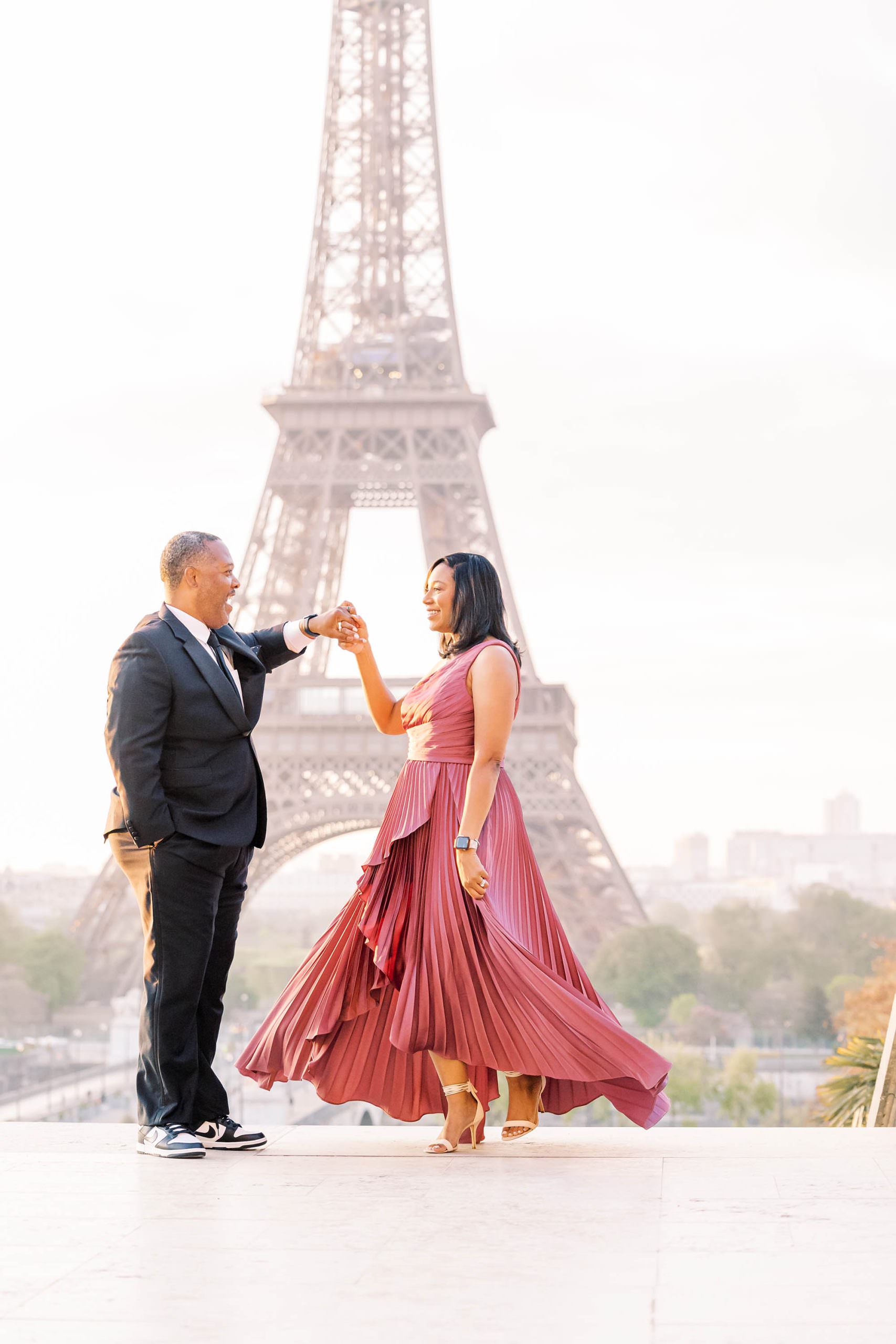 Stylish black couple dancing in front of the Eiffel Tower during their Paris portrait session