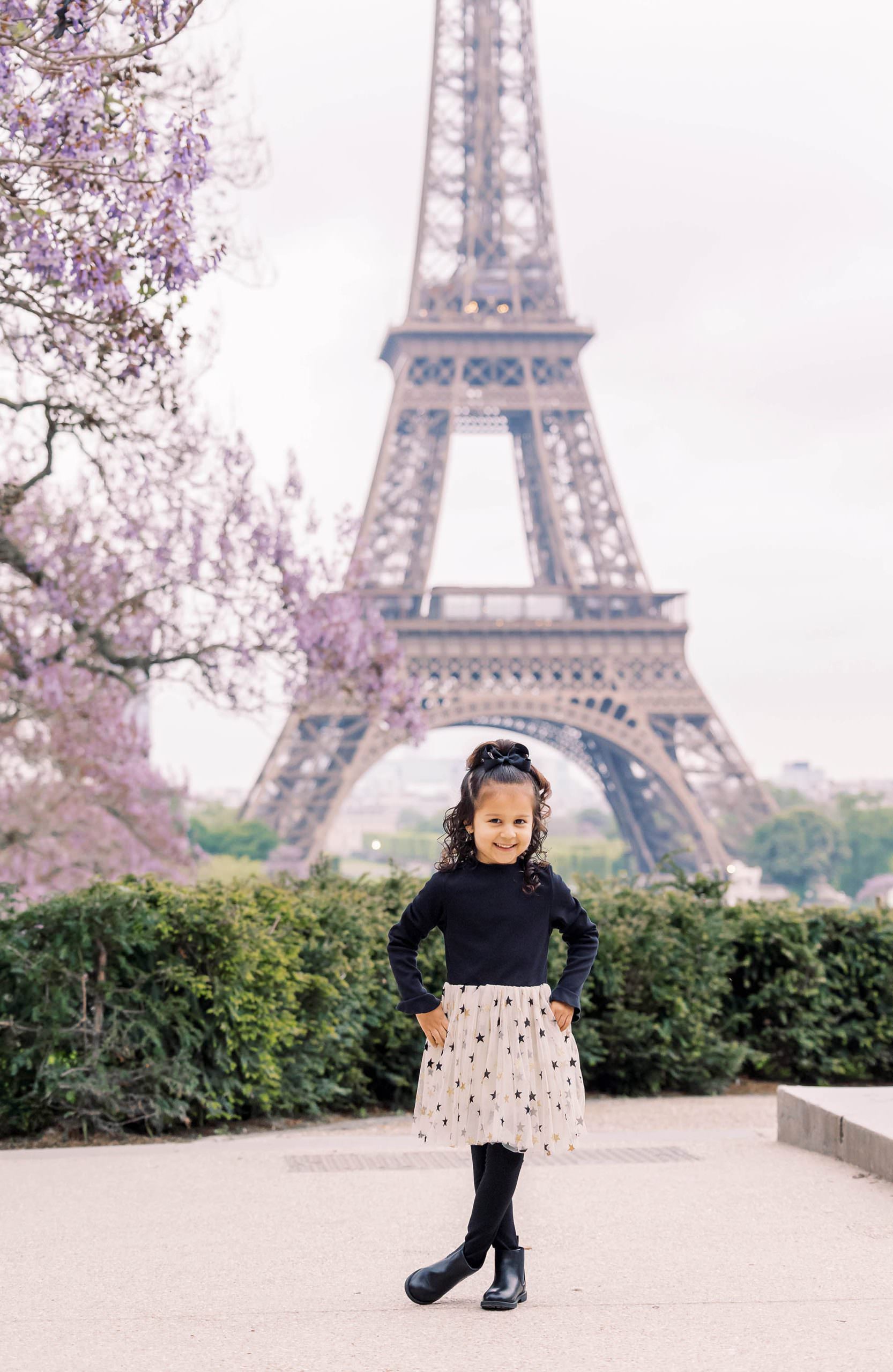 cute girl having her portrait taken at the eiffel tower by a paris photographer