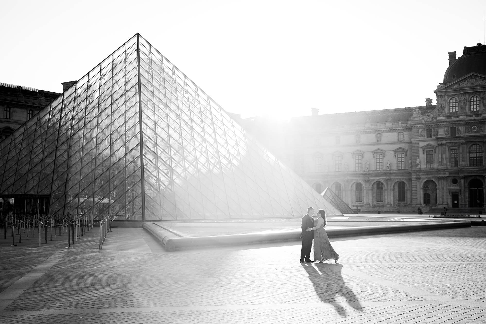 artistic black and white portrait of a couple at the louvre pyramid captured by a paris photographer