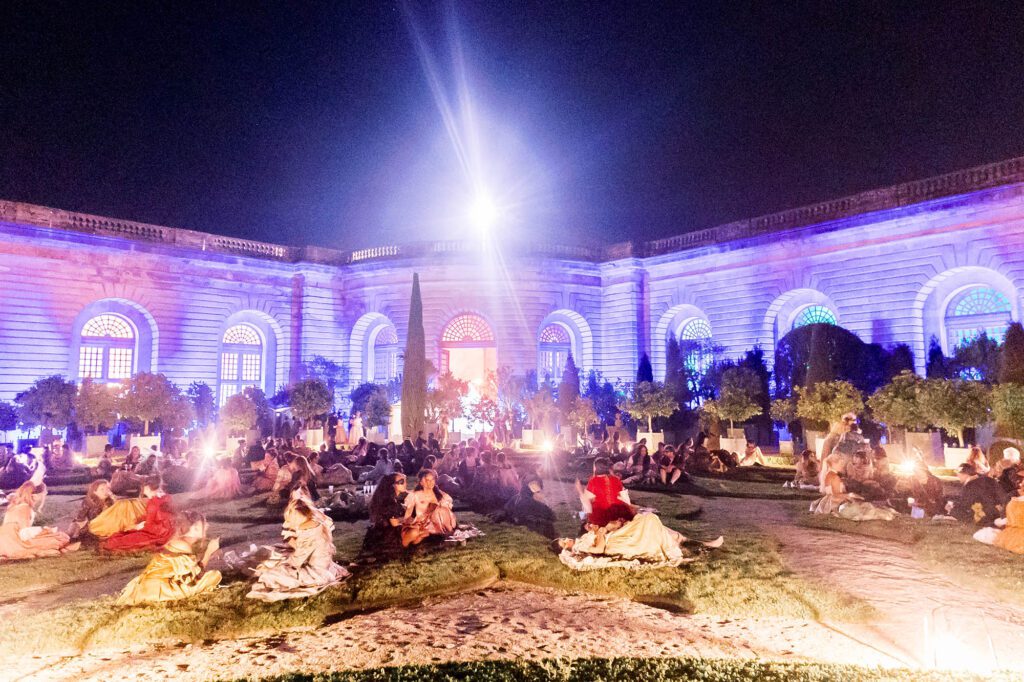 people relaxing in the Orangerie gardens during the masked ball at Versailles