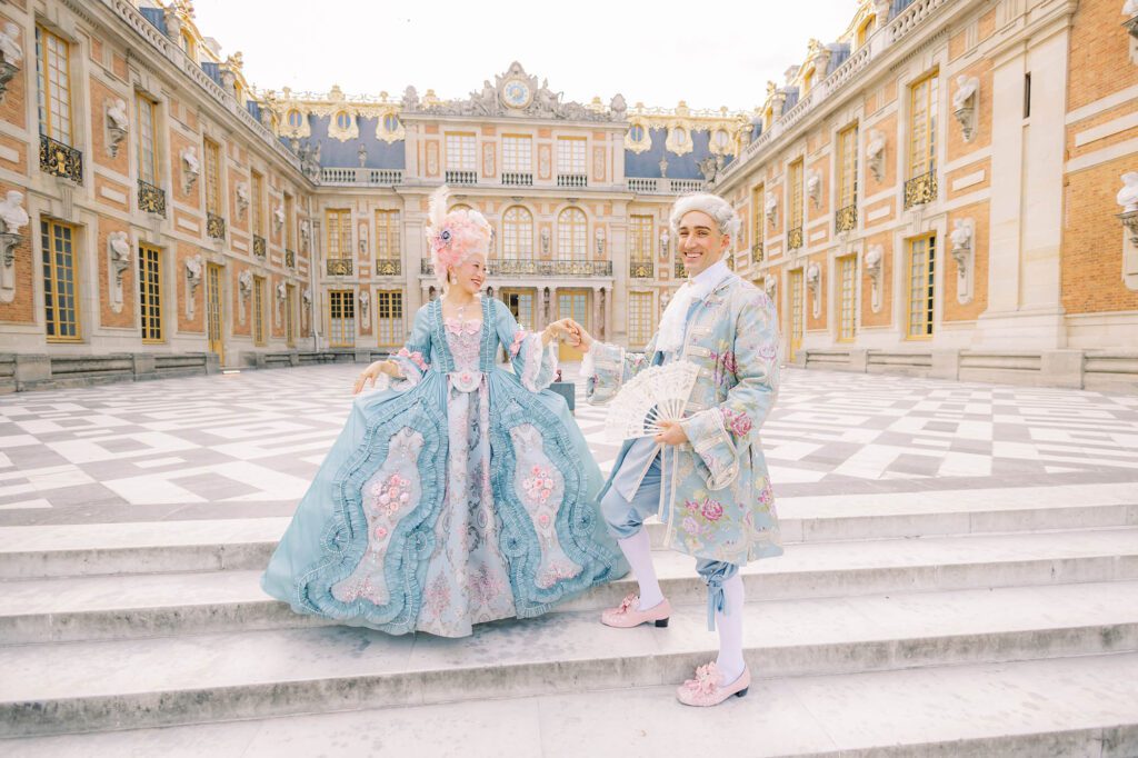 couple dressed in royal costumes for the versailles grand masked ball in the palace courtyard