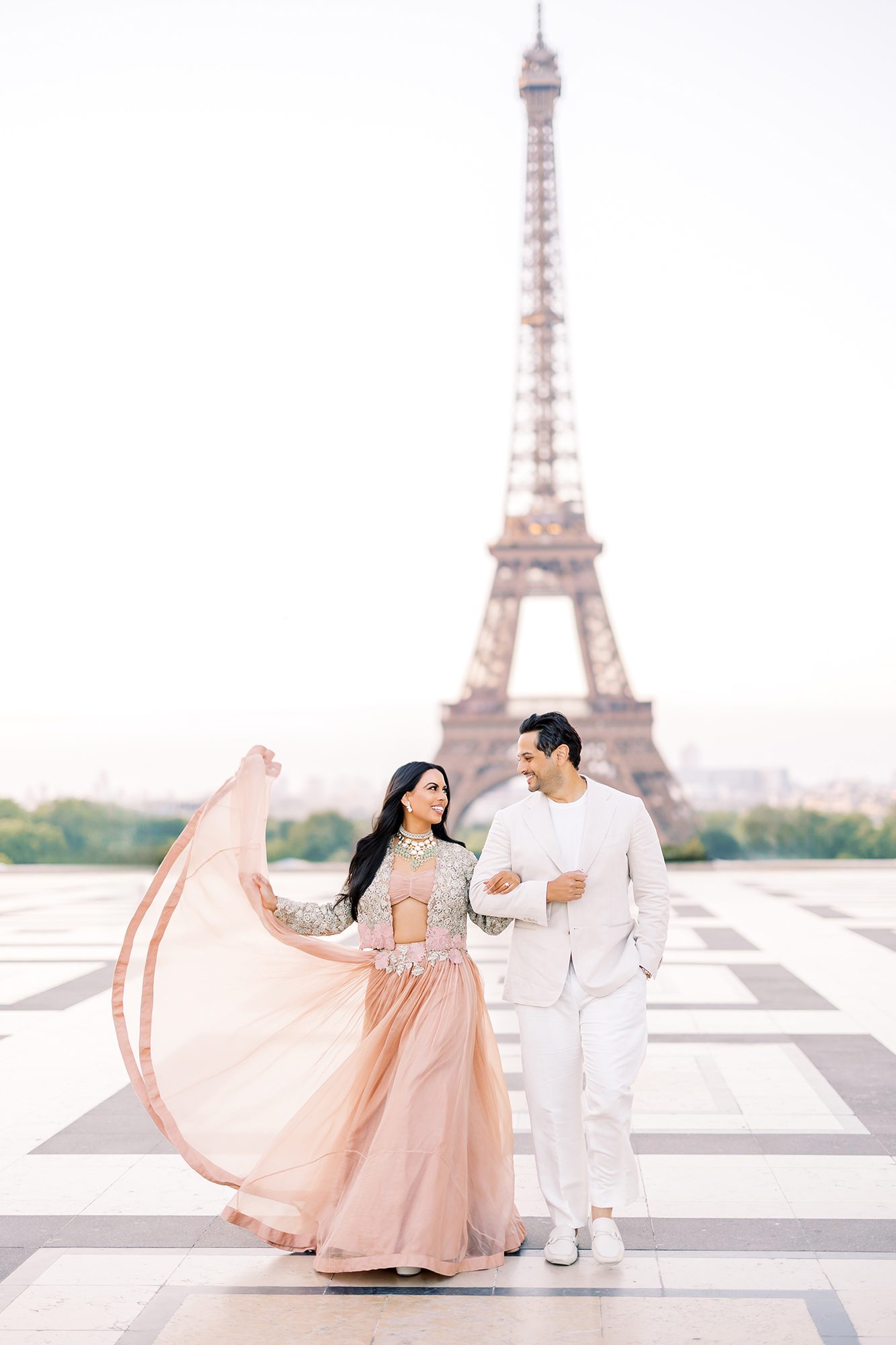 paris couples photo session at the eiffel tower in pink flowy dress and neutral whites for the man