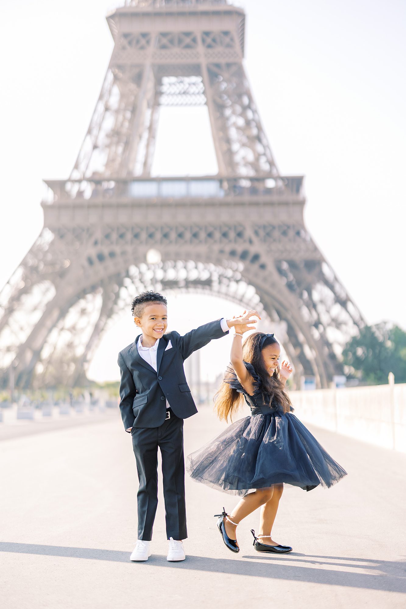 brother and sister dancing for photo during paris family photo shoot in front of eiffel tower