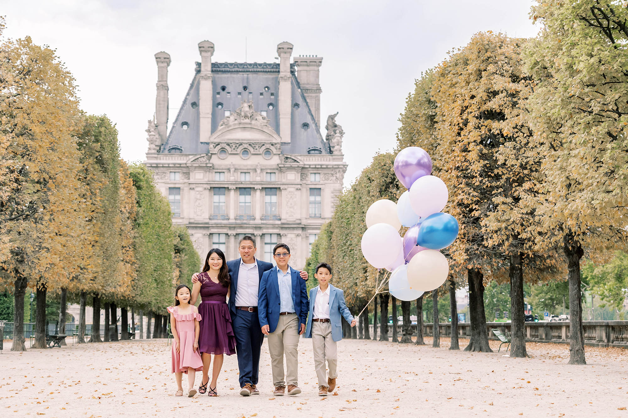 stylish asian family portrait in the tuileries with the louvre in the background during a family portrait session in paris