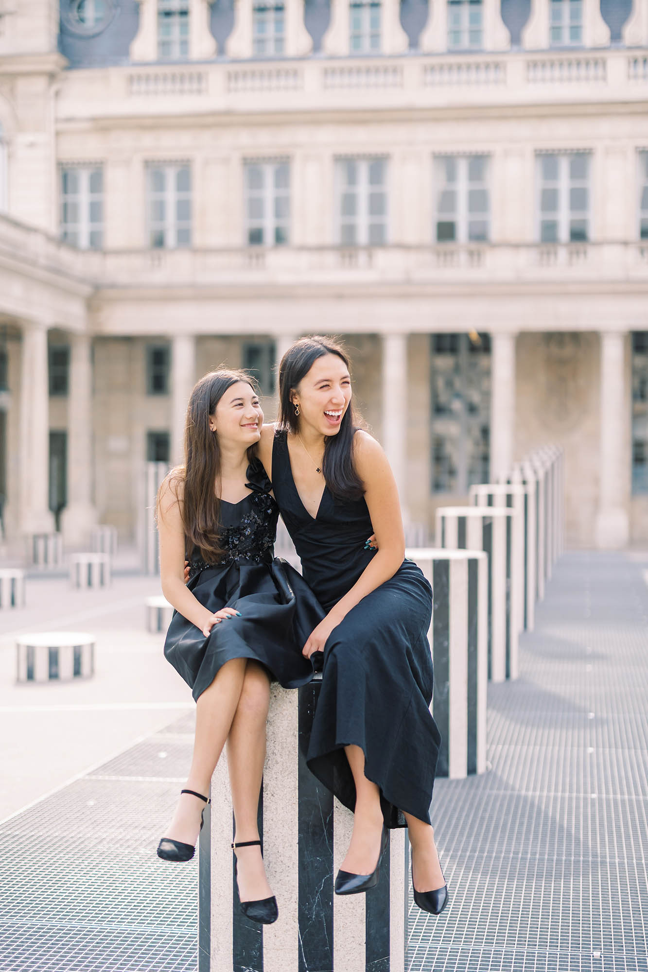 two sisters laughing during their paris family photoshoot in palais royal