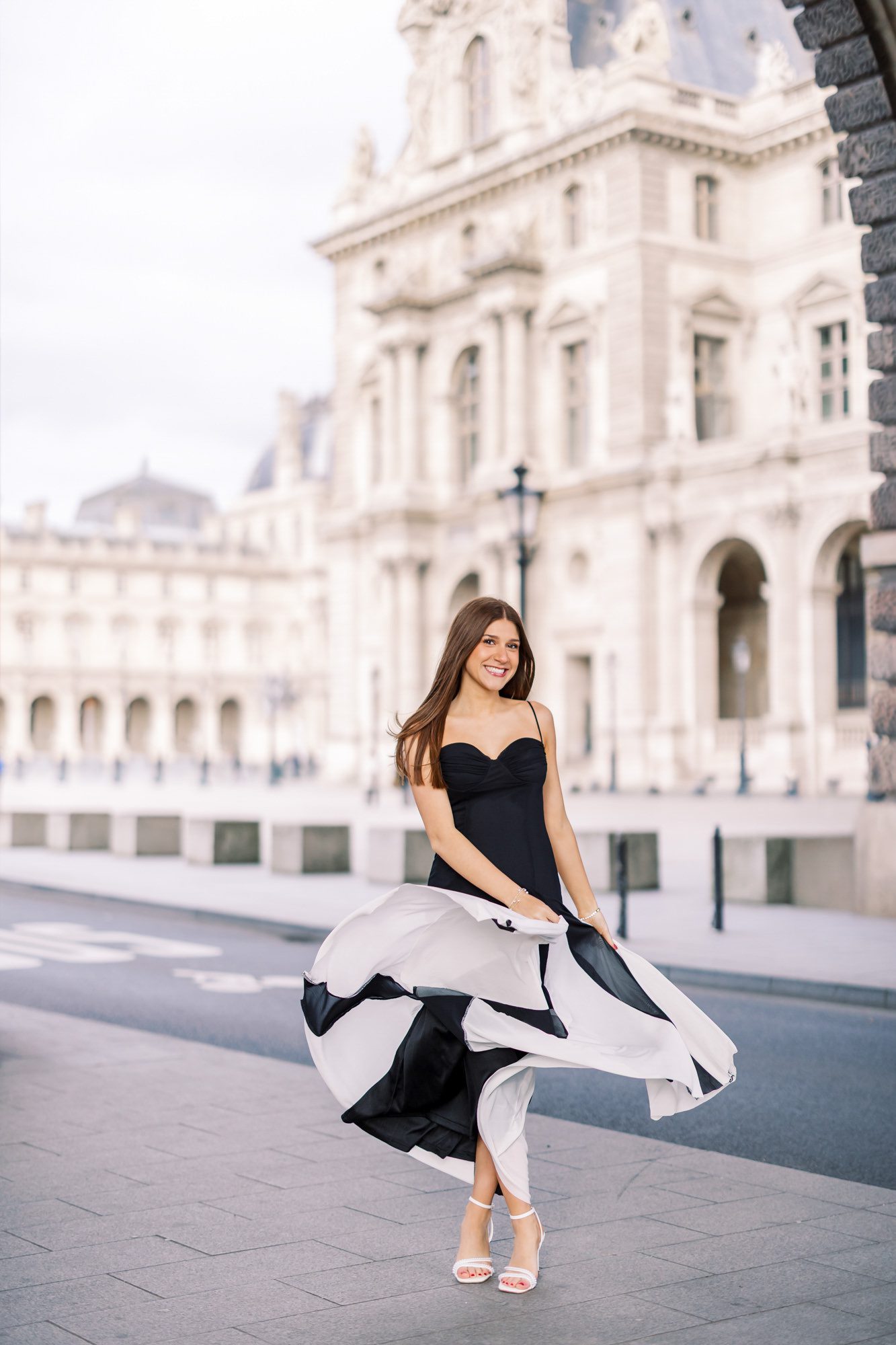 Class of 2026 senior photos showing a girl walking through the Louvre arches.