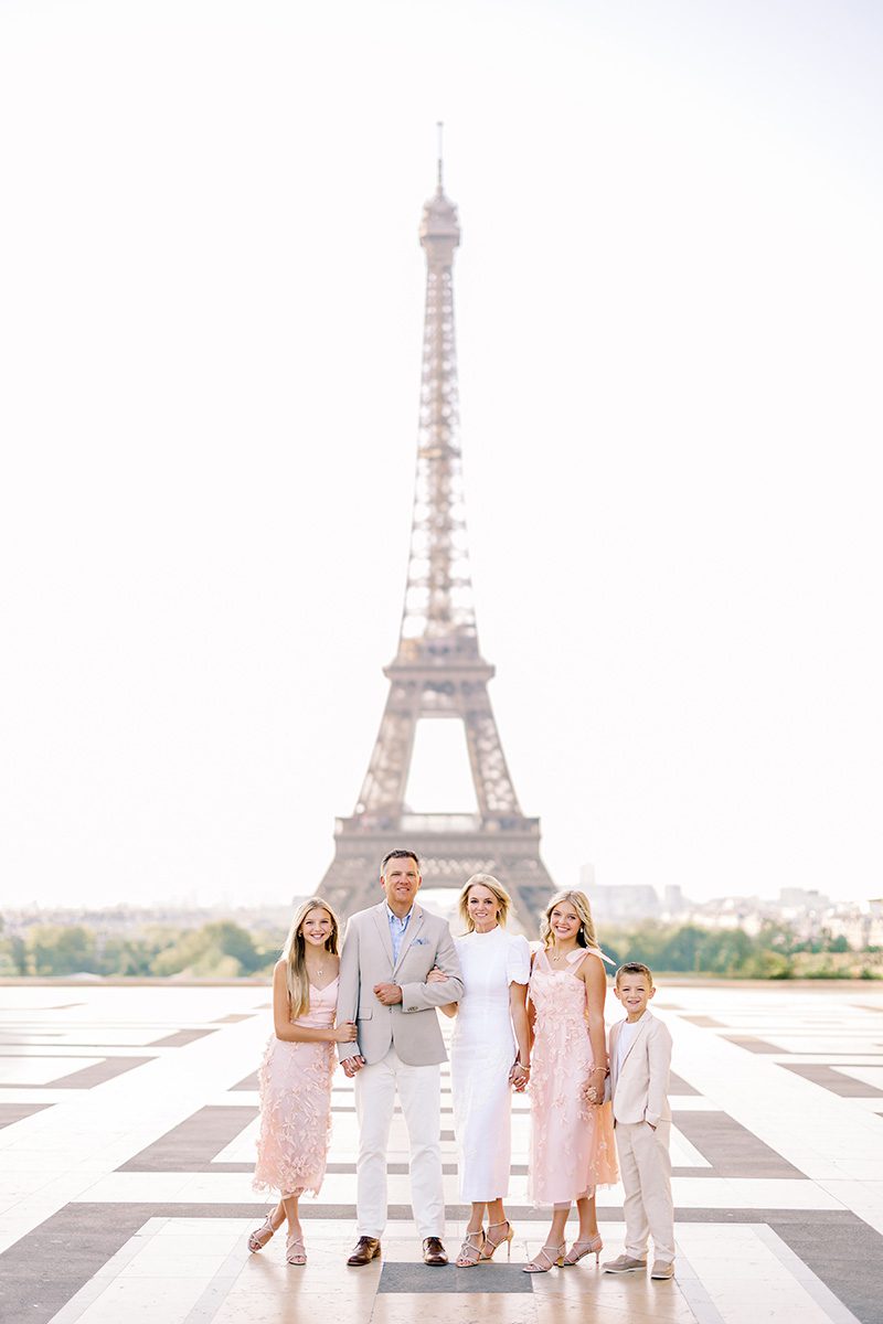 paris photographer review photo of a family of 5 dresses in pinks and beige/white in front of the eiffel tower