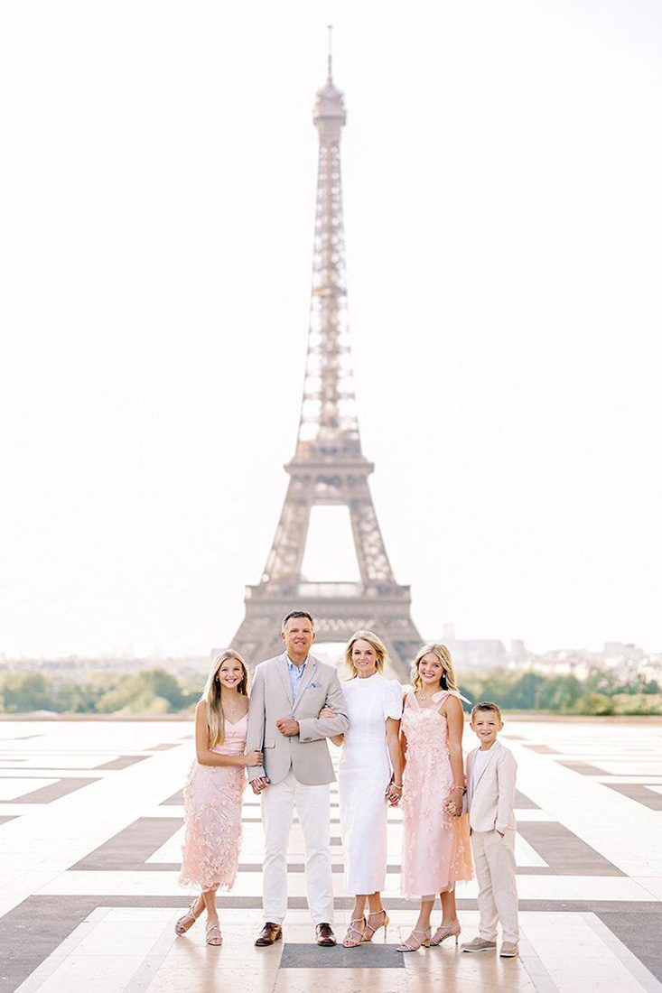 paris family of five dressed in white, beige, and pink posing at the Eiffel Tower for Paris Family Photos